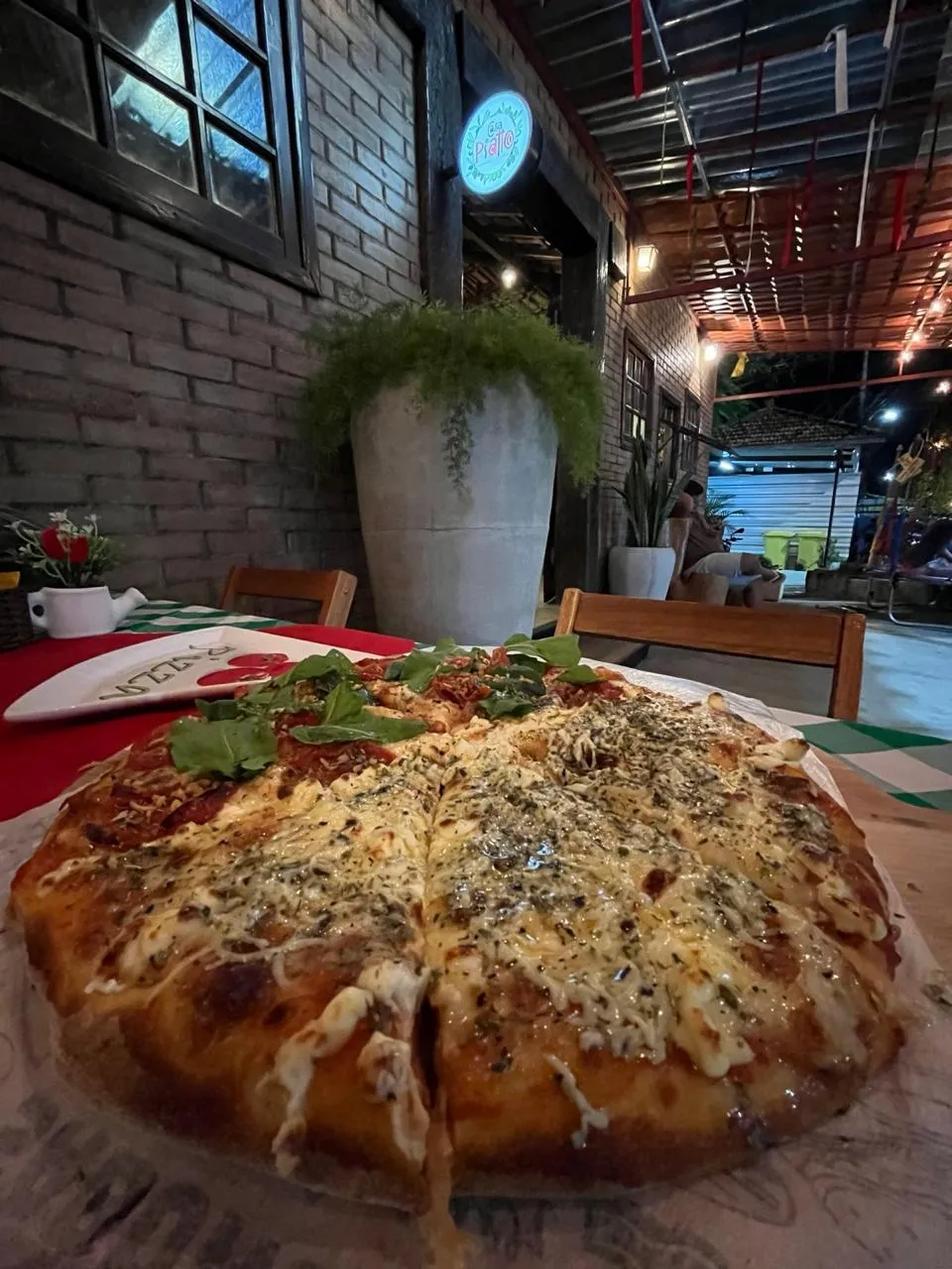 Pizza inteira servida em mesa externa da Casa Piatto